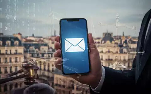 Hand holding a smartphone displaying an email icon, with a subtle overlay of legal scales, against a digital and cityscape background. - Foto: über boerse-global.de