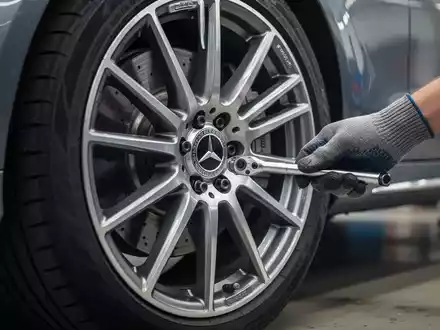 Nahaufnahme eines Mercedes-Benz Rads, an dem ein Mechaniker Radschrauben prĂĽft. - Foto: ĂĽber boerse-global.de