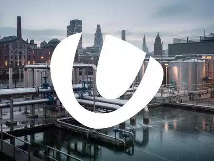 Eine moderne Wasseraufbereitungsanlage in Liverpool bei Regen, mit Rohren und Tanks vor der Stadtsilhouette. - Foto: über boerse-global.de