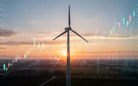 Eine moderne Windkraftanlage bei Sonnenaufgang mit einem Finanzdiagramm im Hintergrund. - Foto: über boerse-global.de