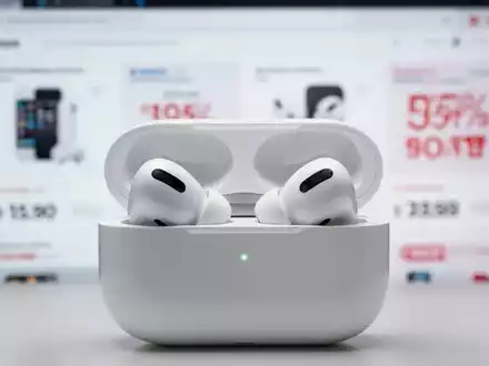 A pair of Apple AirPods Pro 3 earbuds in their white charging case, with a blurred background suggesting retail discounts. - Foto: über boerse-global.de