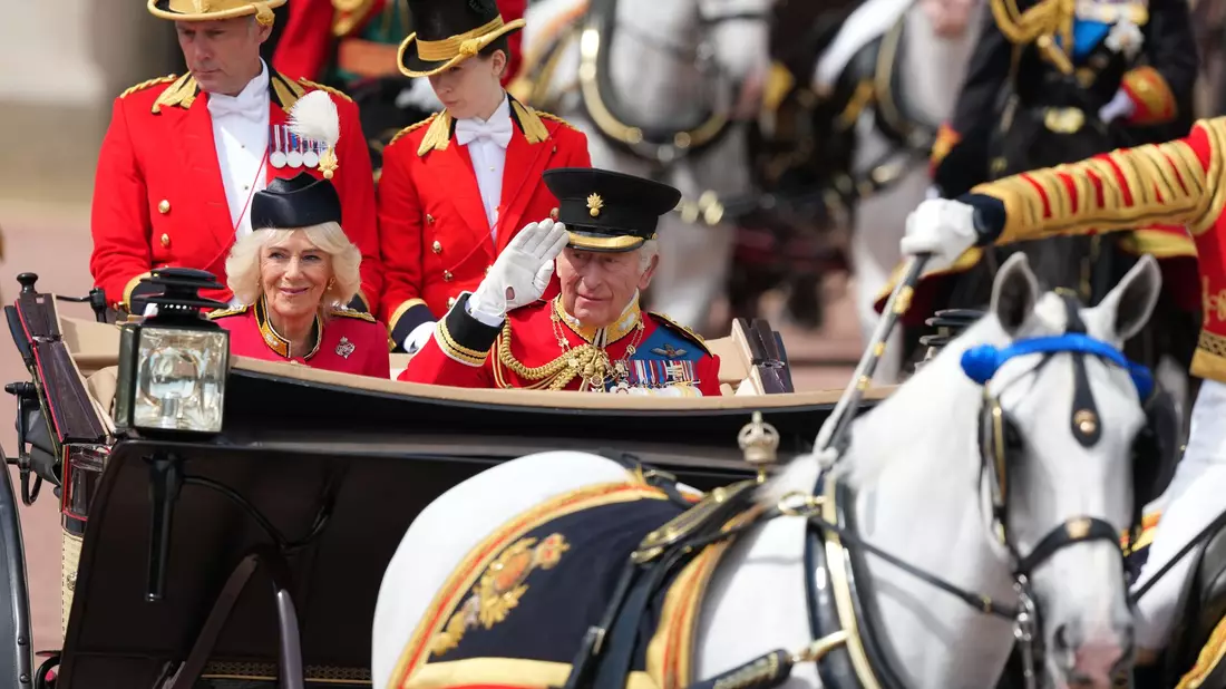 In einer offenen Kutsche fährt das britische Königspaar durch London. - Bild: Kirsty Wigglesworth/AP/dpa