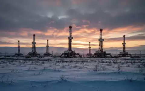 Mehrere Bohrtürme stehen in einer weiten, schneebedeckten Landschaft im Athabasca-Becken bei Sonnenaufgang. - Foto: über boerse-global.de