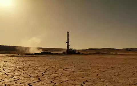 Eine kleine, verlassene Bergbauanlage in einer kargen Landschaft unter einem untergehenden Sonnenlicht, das Stagnation andeutet. - Foto: über boerse-global.de