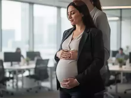 Eine schwangere Frau in professioneller Kleidung berührt ihren Bauch in einem modernen Büro, symbolisierend Mutterschutz und finanzielle Sicherheit. - Foto: über boerse-global.de