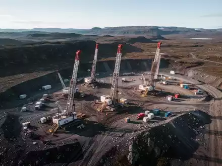 Luftaufnahme eines abgelegenen Bergbau-Explorationsgeländes mit mehreren Bohranlagen in unberührter Natur unter klarem Himmel. - Foto: über boerse-global.de