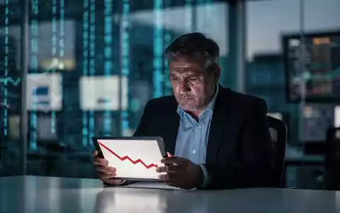 Ein nachdenklicher Geschäftsmann betrachtet ein Tablet mit einem fallenden Aktienkursdiagramm in einem modernen Büro. - Foto: über boerse-global.de
