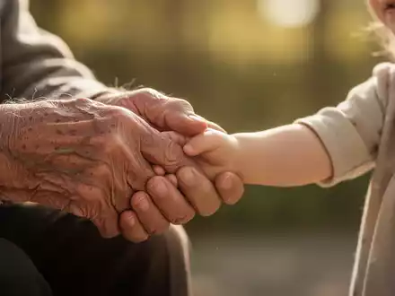 Die Hand einer älteren Person hält sanft die Hand eines Kindes, Symbol für intergenerationelle Verbindung und Fürsorge. - Foto: über boerse-global.de