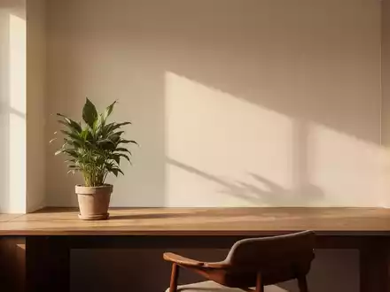 Ein minimalistisches Apartment-Interieur mit klaren Linien, warmem Naturlicht und einer einzelnen Topfpflanze auf einem Holzschreibtisch. - Foto: über boerse-global.de