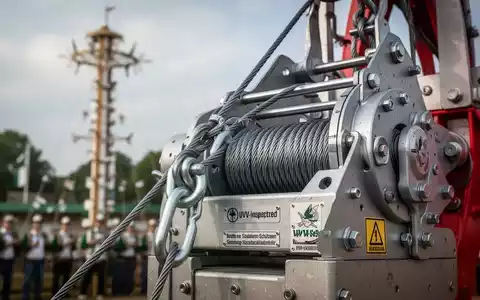 Nahaufnahme einer robusten Seilzuganlage an einer Vogelstange, im Hintergrund verschwommen ein Schützenfest. Fokus auf Sicherheitstechnik. - Foto: über boerse-global.de