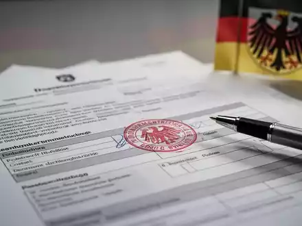 Nahaufnahme von offiziellen Dokumenten mit einem Stempel und Stift, die Bürokratie und Reformen im öffentlichen Dienst symbolisieren. - Foto: über boerse-global.de