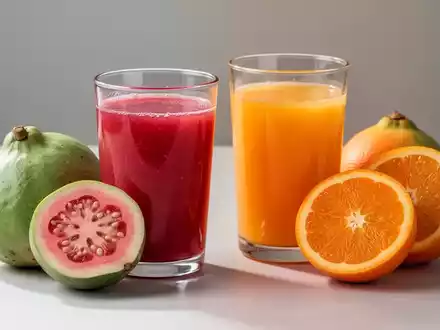 Ein Glas Guavensaft und ein Glas Orangensaft stehen nebeneinander, umgeben von frischen, halbierten Guaven und Orangen. - Foto: über boerse-global.de