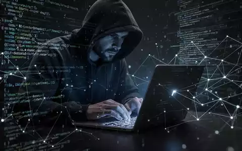 A person in a hoodie typing on a laptop, surrounded by abstract digital code and network lines, symbolizing a cyberattack. - Foto: über boerse-global.de