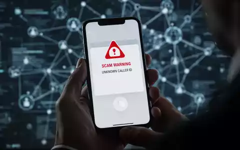 Eine Hand hält ein Smartphone, das eine Warnung vor Betrug oder eine unbekannte Anrufer-ID anzeigt, mit einem unscharfen digitalen Hintergrund. - Foto: über boerse-global.de