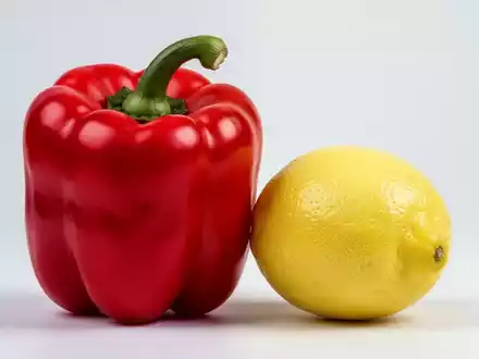 Eine leuchtend rote Paprika liegt neben einer gelben Zitrone. Die Paprika wirkt größer und frischer. - Foto: über boerse-global.de