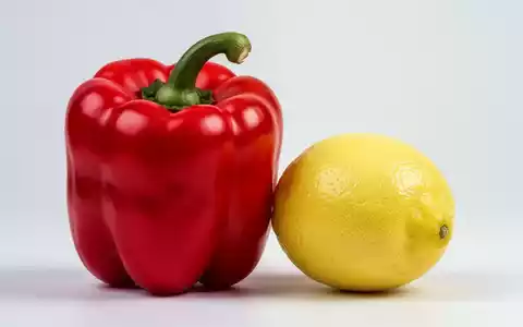 Eine leuchtend rote Paprika liegt neben einer gelben Zitrone. Die Paprika wirkt größer und frischer. - Foto: über boerse-global.de