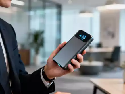 Eine Hand hält eine leuchtende Powerbank in einem modernen Büro, die Technologie und Finanzen symbolisiert. - Foto: über boerse-global.de