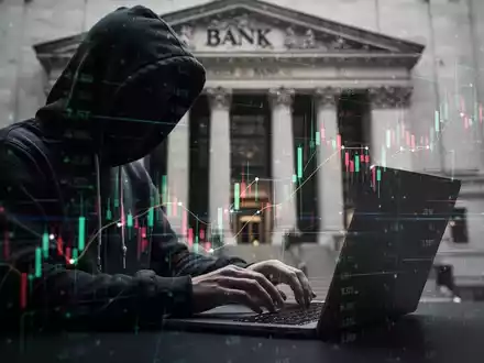 A shadowy figure in a hoodie types on a laptop, surrounded by blurred digital lines and financial data, with a bank in the background. - Foto: über boerse-global.de
