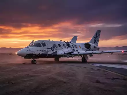 Ein beschädigtes Virgin Galactic Raumschiff auf einer einsamen Landebahn bei Sonnenuntergang, das einen starken Kursrückgang symbolisiert. - Foto: über boerse-global.de