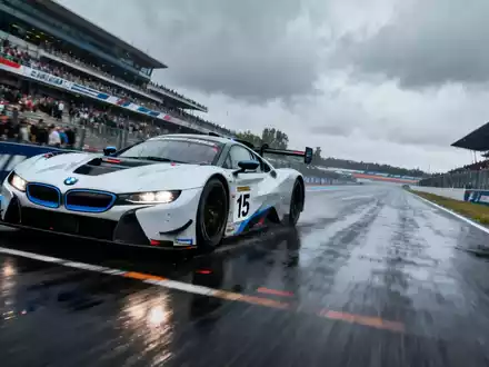 Ein moderner BMW-Rennwagen mit der Nummer 15 fährt auf der Rennstrecke von Le Mans, mit Zuschauern im Hintergrund. - Foto: über boerse-global.de
