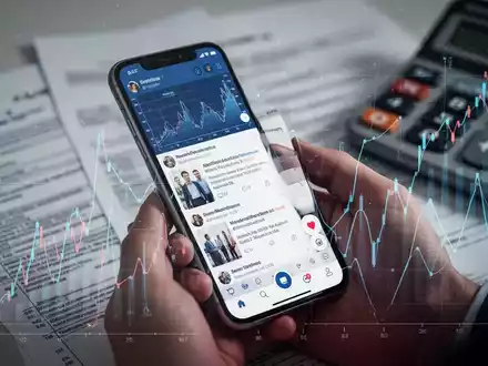 Eine Hand hält ein Smartphone mit Social-Media-Feed und Finanzdaten-Overlay, im Hintergrund verschwommene Steuerdokumente. - Foto: über boerse-global.de