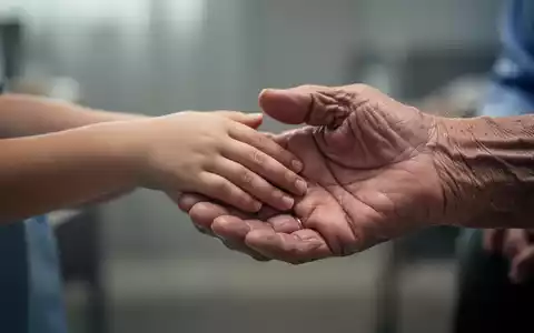 Zwei Hände, eine kleinere, jüngere Hand, die eine größere, ältere Hand berührt, um Verbundenheit und Unterstützung darzustellen. - Foto: über boerse-global.de