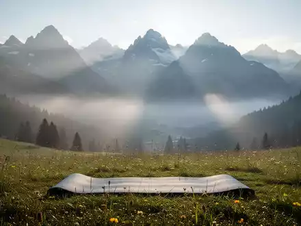 Eine Yogamatte auf einer Bergwiese in den Tiroler Alpen, umgeben von majestätischen Gipfeln und Sonnenlicht. - Foto: über boerse-global.de