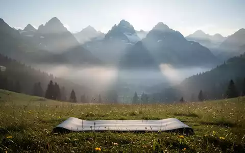 Eine Yogamatte auf einer Bergwiese in den Tiroler Alpen, umgeben von majestätischen Gipfeln und Sonnenlicht. - Foto: über boerse-global.de