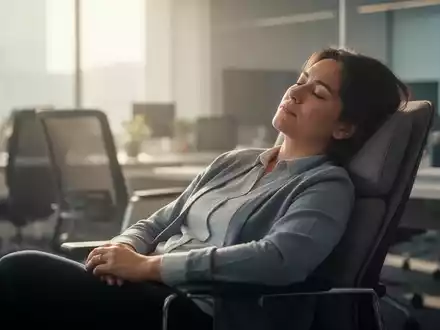 Eine Person macht einen Powernap in einem modernen Bürostuhl, umgeben von sanftem Tageslicht, das Ruhe ausstrahlt. - Foto: über boerse-global.de