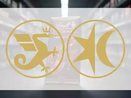 Eine Lindt-Schokoladentafel, die teilweise von einem unscharfen Supermarktgang verdeckt wird, symbolisiert Lieferengpässe. - Foto: über boerse-global.de
