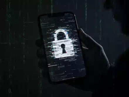 Eine Hand hält ein Smartphone mit einem verzerrten, glitchigen Schloss-Symbol auf dem Bildschirm, das Cyberbedrohungen darstellt. - Foto: über boerse-global.de