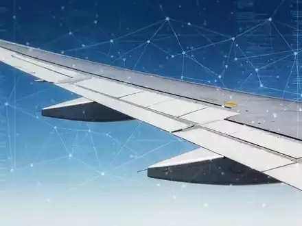 Nahaufnahme eines Flugzeugflügels vor blauem Himmel mit einer subtilen digitalen Überlagerung, die Regulierung und Transparenz symbolisiert. - Foto: über boerse-global.de