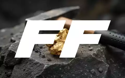 Ein Goldnugget auf dunklem Gestein mit einem Geologenhammer im Hintergrund, der Goldabbau symbolisiert. - Foto: über boerse-global.de