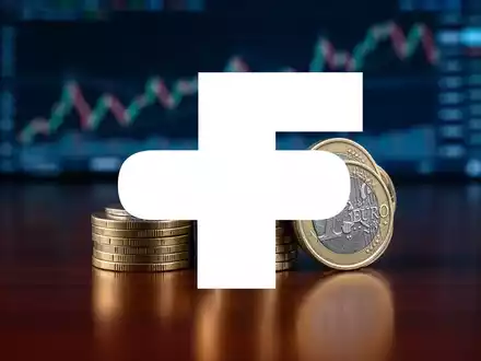 Nahaufnahme von gestapelten Euro-Münzen auf einem Holztisch mit einem verschwommenen Finanzdiagramm im Hintergrund. - Foto: über boerse-global.de