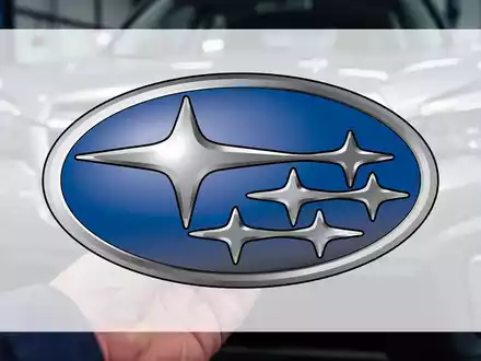 Nahaufnahme eines Subaru Forester-Kühlergrills mit einer Mechanikerhand, die ein kleines Autoteil hält, was auf einen Rückruf hindeutet. - Foto: über boerse-global.de