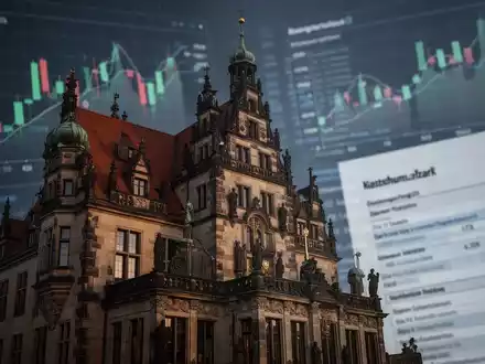 Nahaufnahme der Fassade eines historischen Rathauses, im Hintergrund unscharfe Finanzdiagramme und digitale Steuerformulare. - Foto: über boerse-global.de