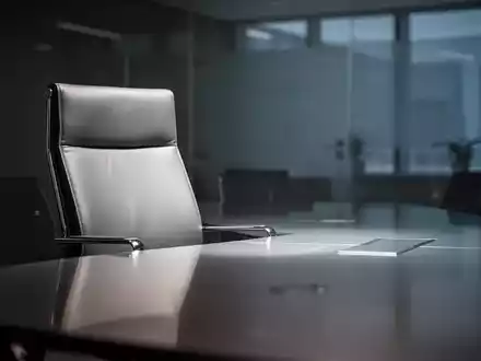 Ein leerer, moderner Chefsessel an einem polierten Konferenztisch in einem schwach beleuchteten Sitzungssaal, der eine neue Ernennung andeutet. - Foto: über boerse-global.de
