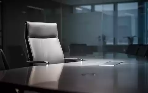 Ein leerer, moderner Chefsessel an einem polierten Konferenztisch in einem schwach beleuchteten Sitzungssaal, der eine neue Ernennung andeutet. - Foto: über boerse-global.de