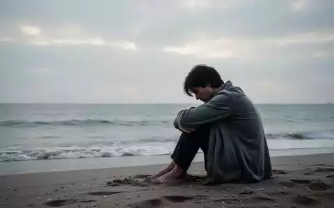 Eine Person sitzt allein am Strand und blickt aufs Meer, Haltung vermittelt Erschöpfung und Nachdenklichkeit unter bewölktem Himmel. - Foto: über boerse-global.de