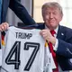 Trump zeigt sein Geschenk zum 80. Geburtstag.  - Bild: Michael Kappeler/dpa-Pool/dpa
