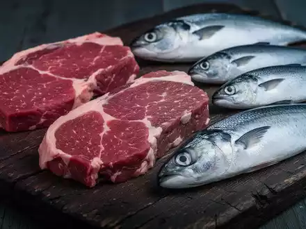 Eine Nahaufnahme von frischem Fleisch und verschiedenen Fischsorten auf einem dunklen Holzbrett, die die Lebensmittelausgaben repräsentieren. - Foto: über boerse-global.de
