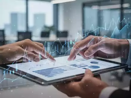 Nahaufnahme von Händen, die ein Tablet mit Finanzdaten und Diagrammen halten, im Hintergrund ein unscharfes Büro. - Foto: über boerse-global.de