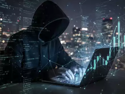 A shadowy figure in a hoodie typing on a laptop, surrounded by abstract digital code, symbolizing cyberattacks on the financial industry. - Foto: über boerse-global.de