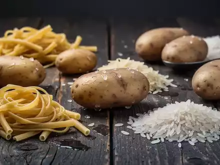 Nahaufnahme von abgekühlten, kohlenhydratreichen Lebensmitteln wie Nudeln, Kartoffeln und Reis auf einem Holztisch. - Foto: über boerse-global.de