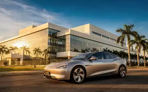Ein glänzendes BYD Elektrofahrzeug vor einer modernen Fabrik in Brasilien, umgeben von Palmen unter blauem Himmel. - Foto: über boerse-global.de