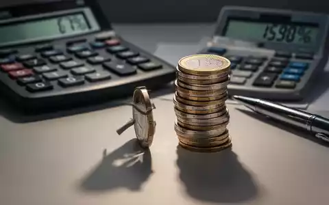 Ein Stapel Euro-Münzen mit einem Taschenrechner und einem Stift im Hintergrund, der steigende Kosten symbolisiert. - Foto: über boerse-global.de