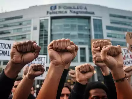 Nahaufnahme verschiedener Hände, einige zu Fäusten geballt, andere halten Protestschilder vor einem unscharfen Hintergrund. - Foto: über boerse-global.de