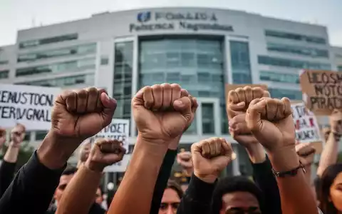 Nahaufnahme verschiedener Hände, einige zu Fäusten geballt, andere halten Protestschilder vor einem unscharfen Hintergrund. - Foto: über boerse-global.de