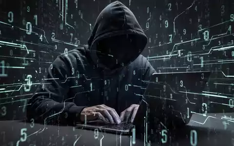 A person in a dark hoodie typing on a laptop, with glowing digital lines and numbers around them, representing cybercrime. - Foto: über boerse-global.de