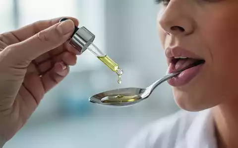 Eine Hand hält ein Tropffläschchen mit CBD-Öl, ein Tropfen fällt in einen Löffel. Fokus auf Wellness und Schmerzlinderung. - Foto: über boerse-global.de